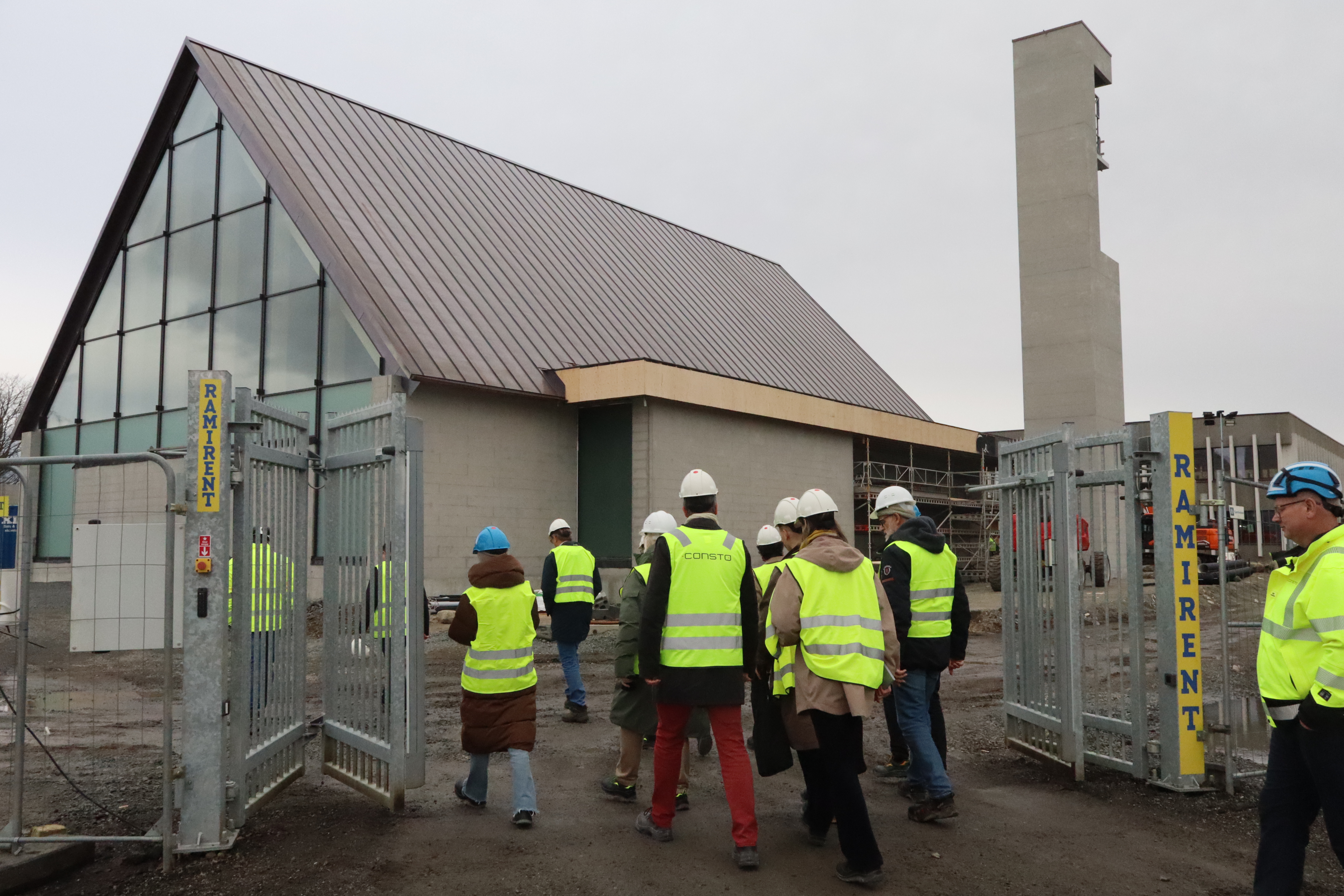 Menneske med refleksvest og hjelm på veg inn til den nye kyrkja